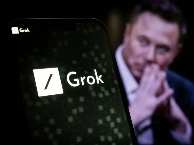 Imagen de un celular con el logo de Grok y de fondo Elon Musk sentado con su típica pose 